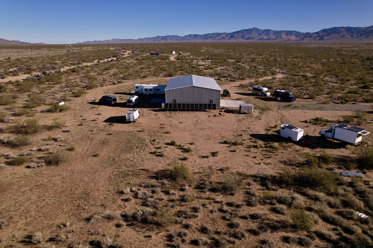 Aerial view of the Roamstead: the shop building with rigs parked around it, desert and mountains beyond